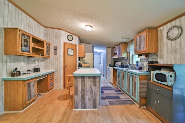 kitchen featuring light hardwood / wood-style floors, a center island, sink, crown molding, and white appliances