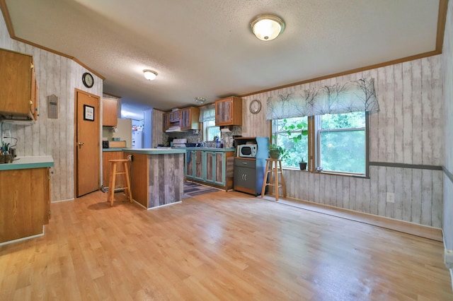 kitchen with kitchen peninsula, a kitchen breakfast bar, a textured ceiling, and light hardwood / wood-style flooring