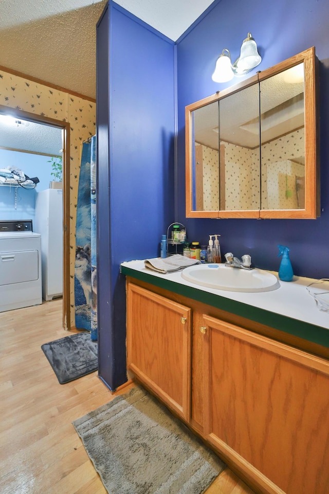 bathroom featuring vanity, washer / dryer, a textured ceiling, and hardwood / wood-style floors