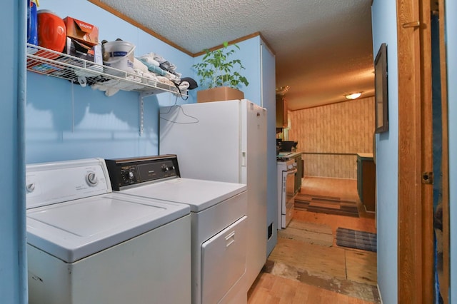 clothes washing area featuring washing machine and dryer, a textured ceiling, and light hardwood / wood-style flooring