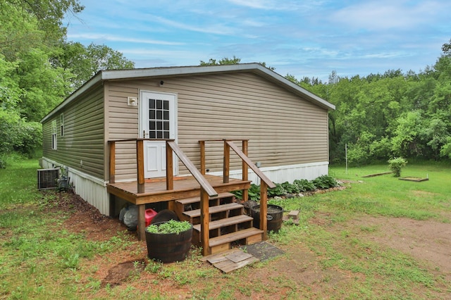 rear view of house with central AC and a yard