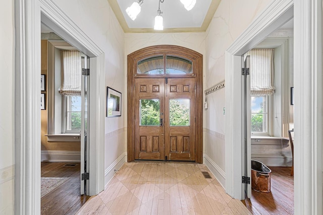 entryway featuring visible vents, crown molding, and light wood-style flooring