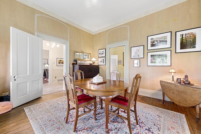 dining room featuring crown molding, wood finished floors, and baseboards