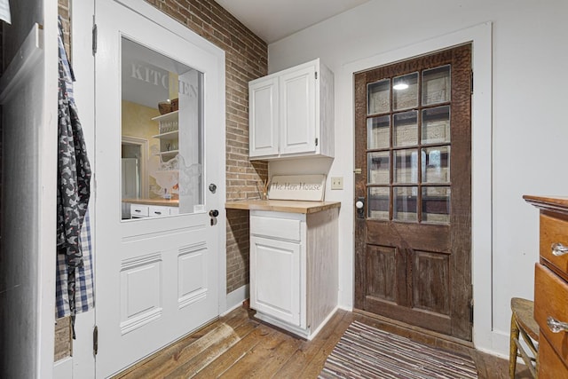 entryway with light wood finished floors and brick wall