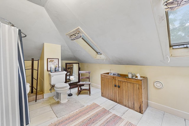 bathroom with lofted ceiling with skylight, baseboards, and toilet