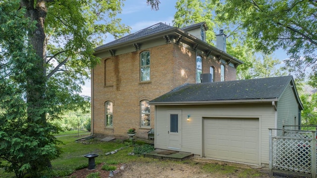 back of property featuring a garage, brick siding, and a chimney