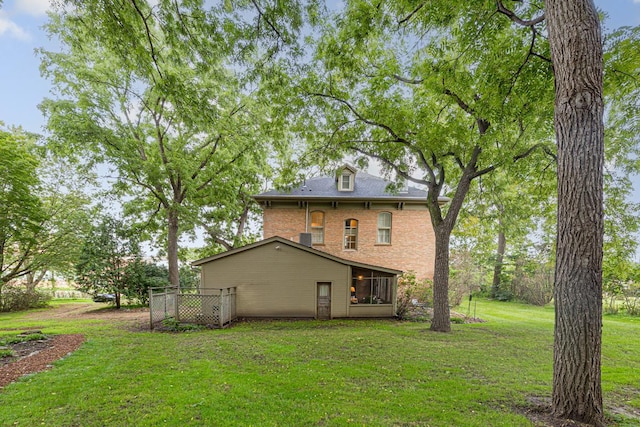 rear view of property with brick siding, a yard, and fence