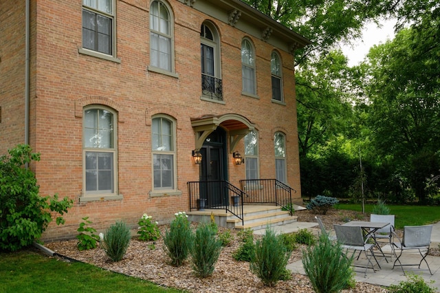 view of front of house with brick siding and a patio