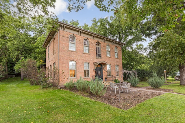 italianate house featuring a patio, a front lawn, and brick siding