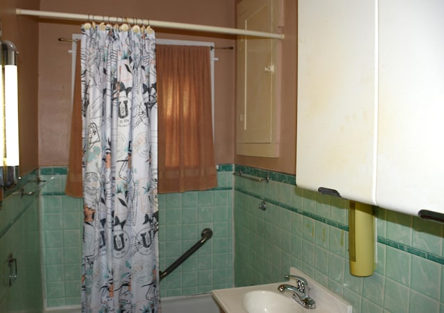 bathroom with sink, shower / tub combo with curtain, and tile walls