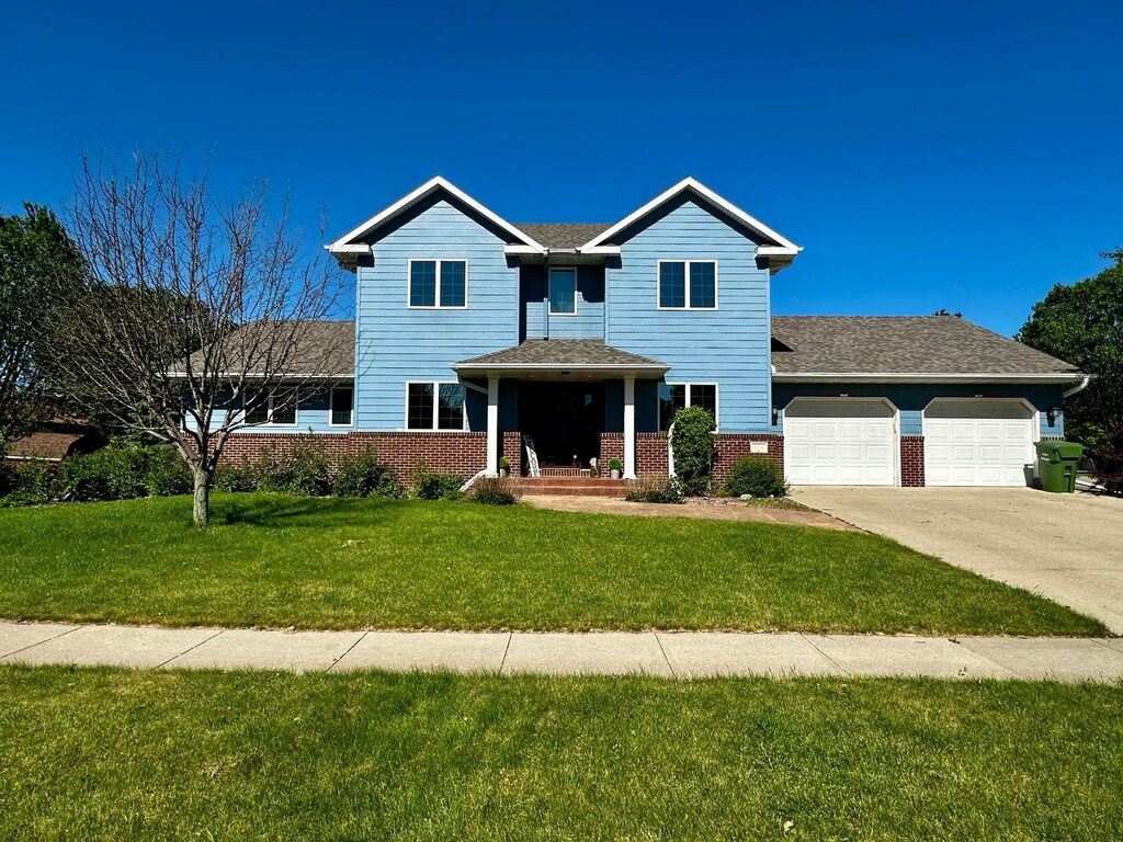 810 Briarwood Dr, Worthington, MN 56187 - traditional-style home with brick siding, a shingled roof, a front lawn, a garage, and driveway