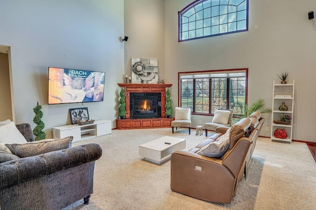 carpeted living area featuring baseboards, a lit fireplace, and a high ceiling