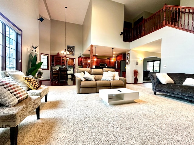 living area featuring baseboards, light carpet, and arched walkways