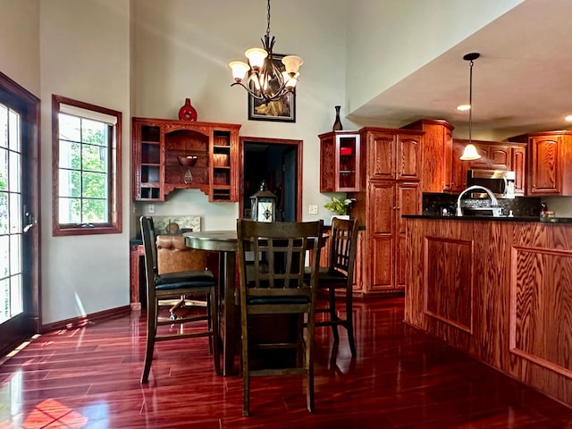 dining room featuring dark wood-type flooring, baseboards, a towering ceiling, and a chandelier