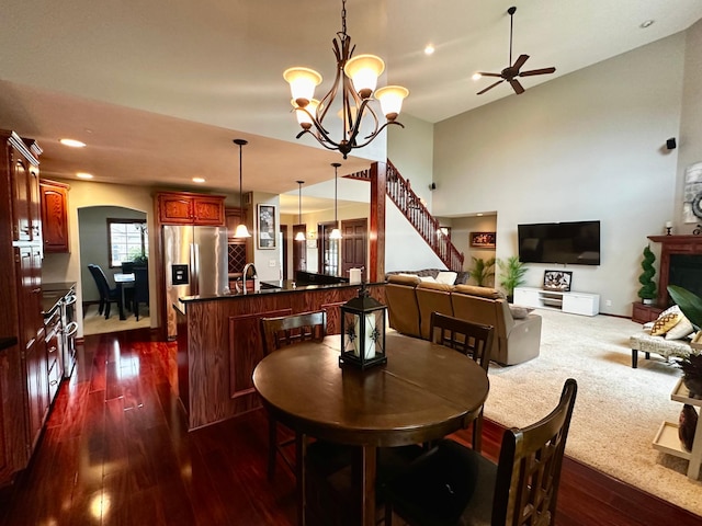 dining area with ceiling fan with notable chandelier, recessed lighting, stairway, arched walkways, and dark wood-style flooring