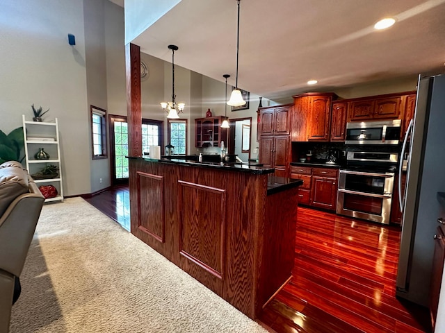 kitchen featuring dark wood-type flooring, dark countertops, open floor plan, recessed lighting, and appliances with stainless steel finishes