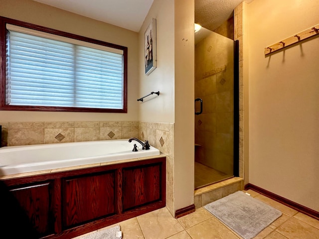 bathroom with tile patterned floors, baseboards, a garden tub, and a shower stall