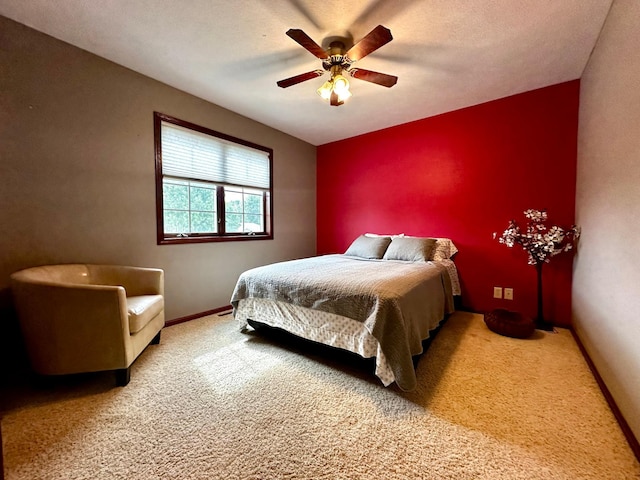 carpeted bedroom with an accent wall, a ceiling fan, baseboards, and a textured ceiling