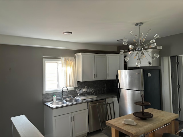 kitchen with tasteful backsplash, stainless steel appliances, white cabinetry, an inviting chandelier, and sink