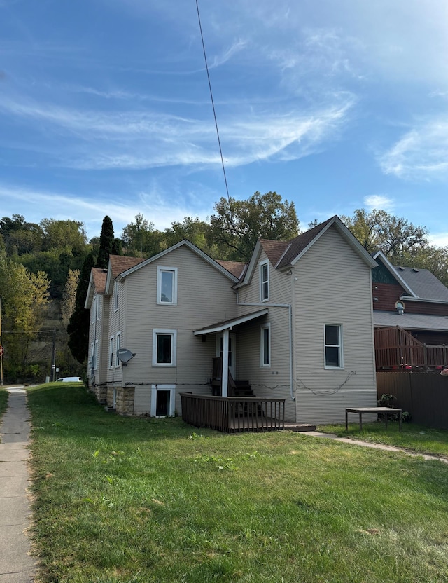 rear view of house featuring a wooden deck and a yard