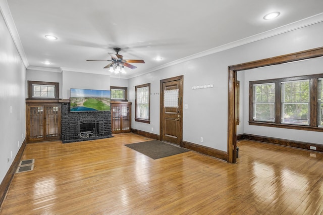 foyer entrance featuring ceiling fan, a fireplace, light wood-type flooring, and crown molding