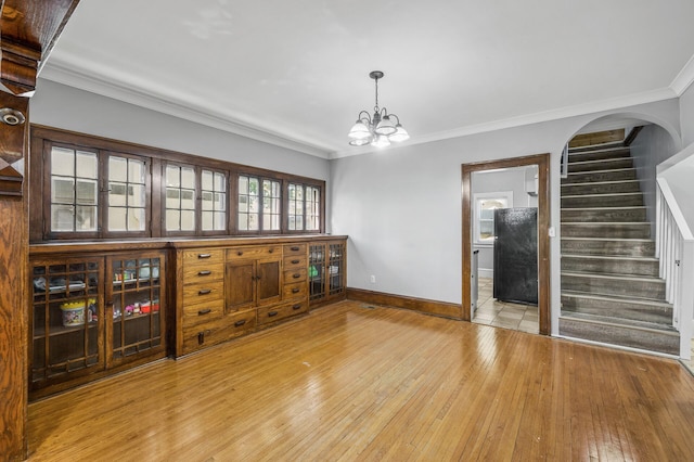 interior space featuring an inviting chandelier, light hardwood / wood-style flooring, and ornamental molding