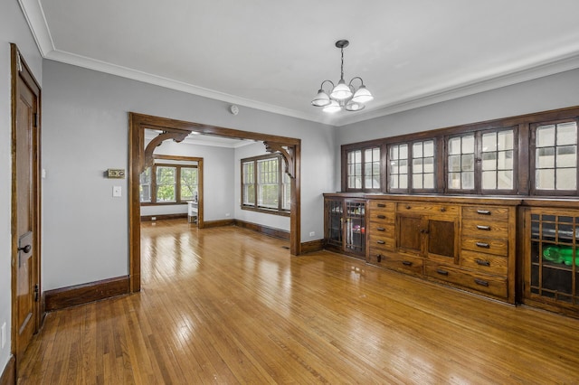 unfurnished room featuring hardwood / wood-style flooring, crown molding, and a notable chandelier