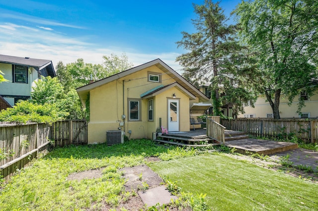 view of front of home featuring a wooden deck, cooling unit, and a front lawn