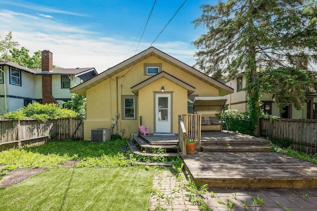 rear view of house featuring central AC unit, a yard, and a wooden deck