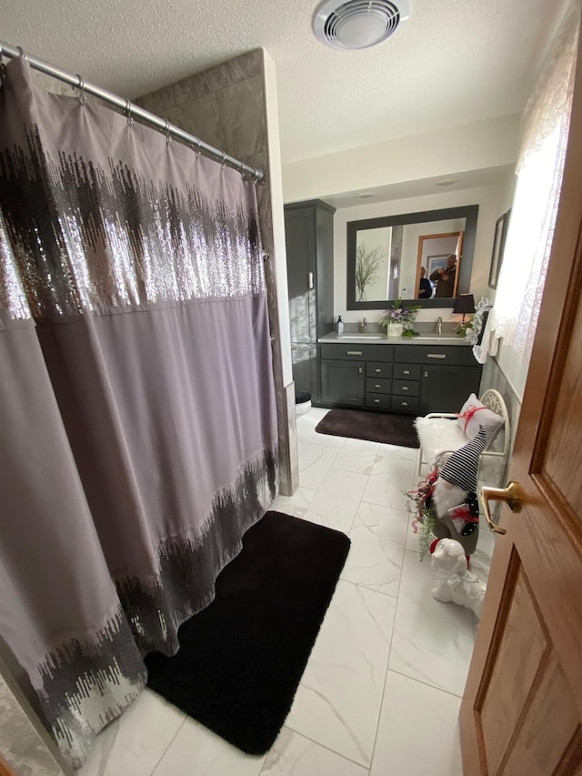 bathroom featuring a textured ceiling, vanity, and a shower with curtain