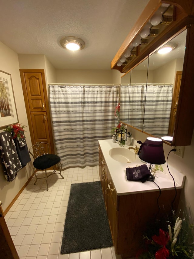 bathroom featuring tile patterned flooring, vanity, and a textured ceiling