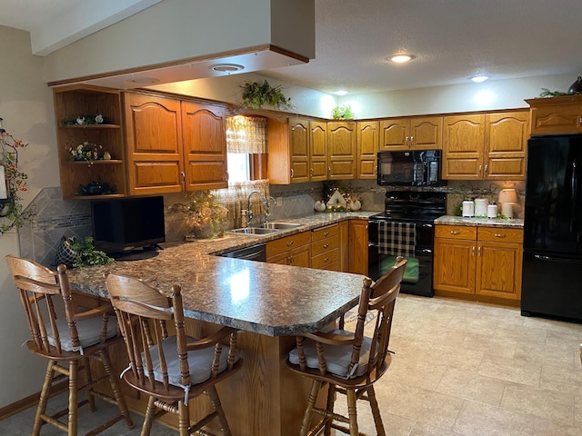 kitchen with black appliances, a peninsula, a sink, and brown cabinets