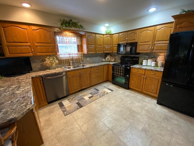 kitchen with black appliances, tasteful backsplash, a sink, and brown cabinets