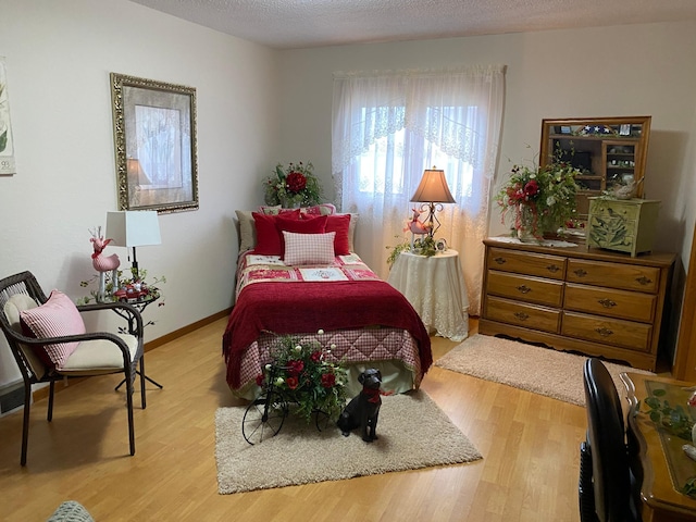 bedroom with a textured ceiling, baseboards, and wood finished floors