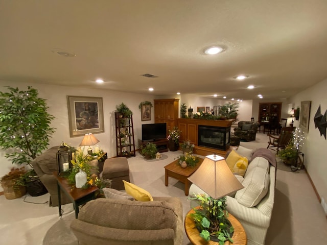 living room featuring light carpet, a glass covered fireplace, visible vents, and recessed lighting