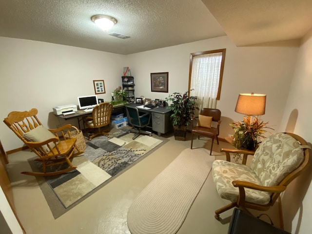 home office with light carpet, visible vents, and a textured ceiling