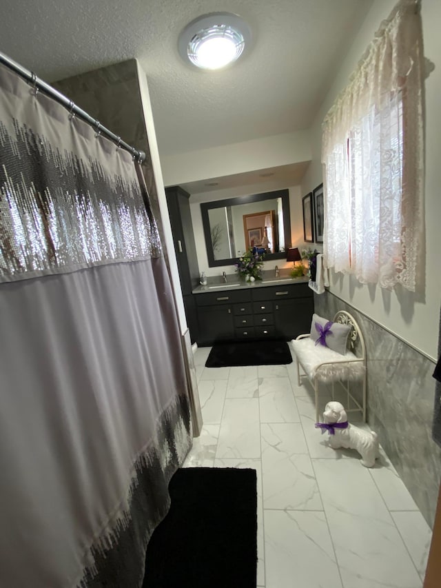 bathroom with a textured ceiling, marble finish floor, vanity, and a shower with curtain