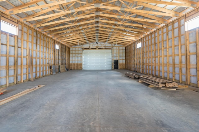 miscellaneous room with vaulted ceiling, concrete flooring, and a garage