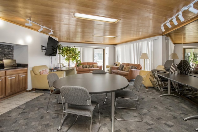 carpeted dining space with track lighting, a wealth of natural light, and wood ceiling