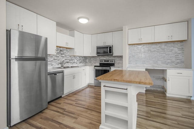 kitchen with wood counters, sink, light hardwood / wood-style flooring, appliances with stainless steel finishes, and white cabinetry