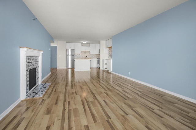 unfurnished living room featuring a tiled fireplace and light hardwood / wood-style floors