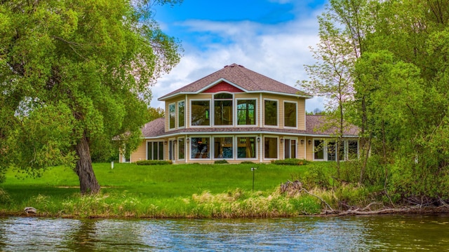 rear view of property with a water view and a lawn