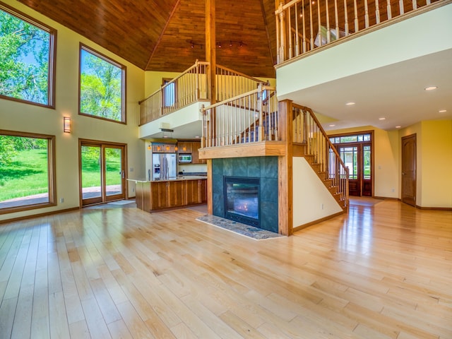 unfurnished living room featuring a high ceiling, light hardwood / wood-style floors, and wooden ceiling