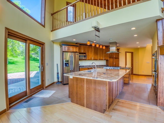 kitchen featuring sink, appliances with stainless steel finishes, an island with sink, island range hood, and light stone counters