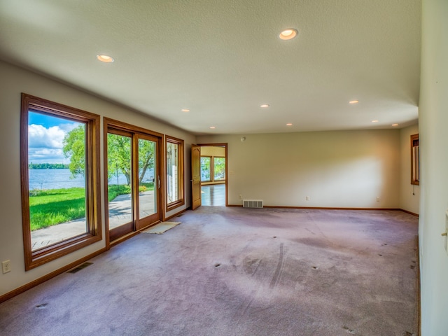 spare room featuring light carpet and a water view