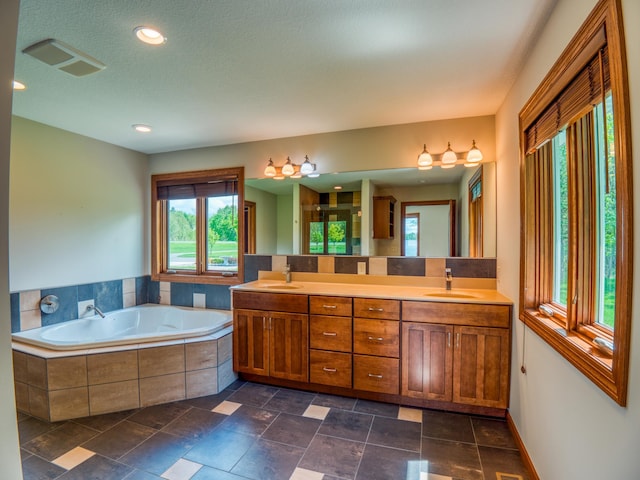 bathroom with tiled tub, vanity, and a textured ceiling