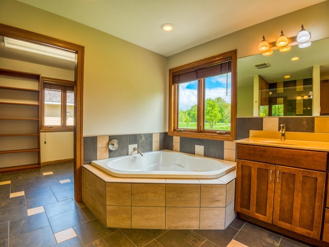 bathroom featuring tiled bath and vanity