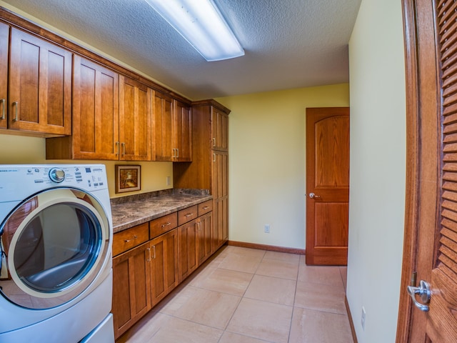 washroom with light tile patterned flooring, cabinets, a textured ceiling, and washer / clothes dryer