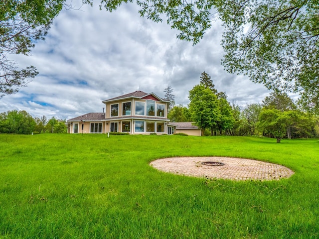 back of house featuring an outdoor fire pit and a lawn