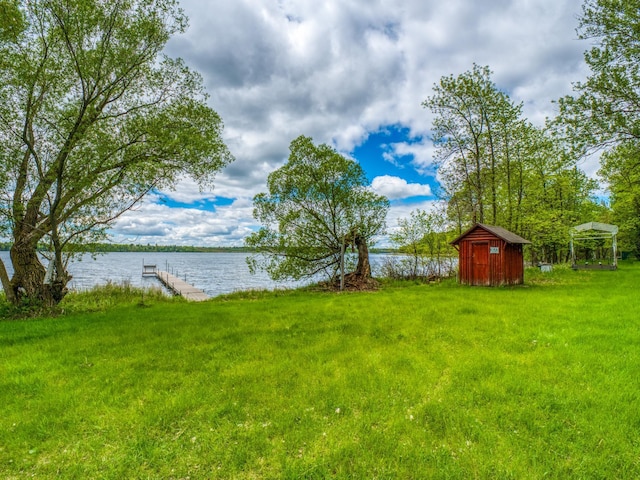 view of yard featuring a boat dock, a water view, and a storage unit